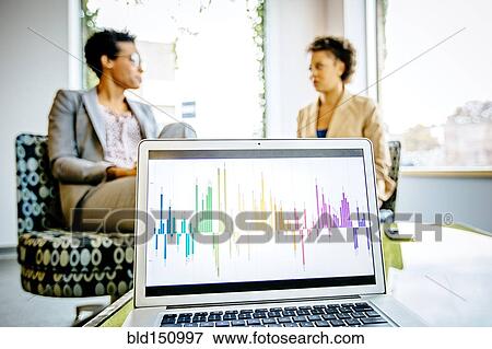 Businesswomen sitting behind laptop in office lobby View Large Photo Image Stock Photo - Businesswomen sitting behind laptop in office lobby. Fotosearch