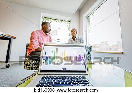 Businesswomen sitting behind laptop in office lobby View Large Photo Image Stock Photo - Businesswomen sitting behind laptop in office lobby. Fotosearch