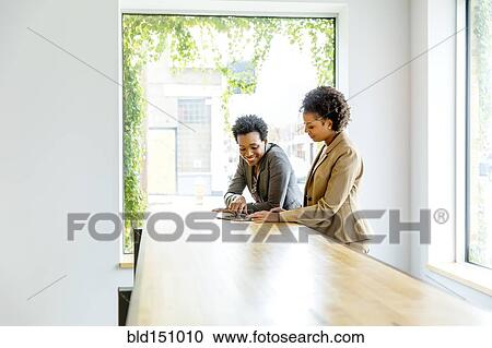 Stock Image - Businesswomen using digital tablet in office. Fotosearch