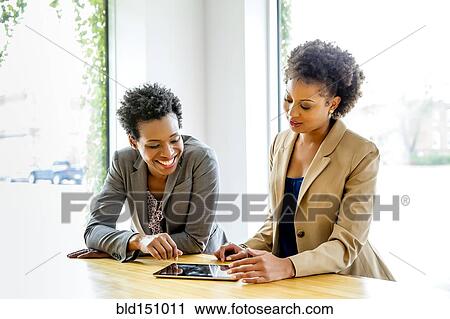 Stock Image - Businesswomen using digital tablet in office. Fotosearch