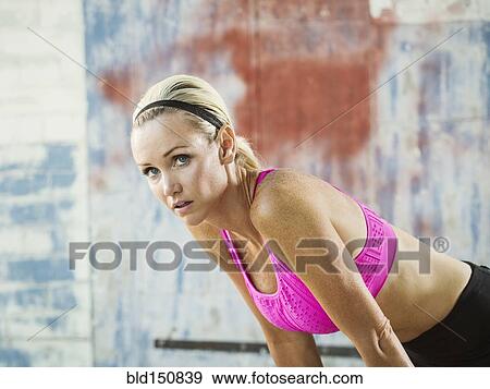 Stock Photo - Caucasian athlete resting in warehouse. Fotosearch