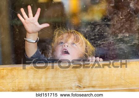 Stock Photography - Caucasian baby pressing hand to window. Fotosearch