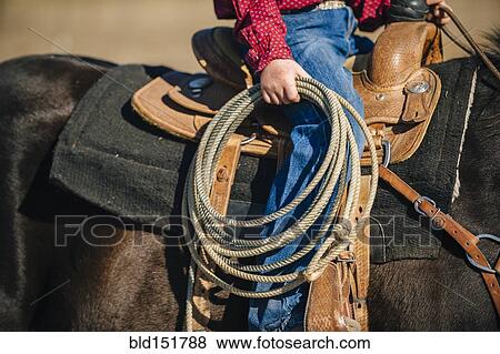 Stock Photo - Caucasian boy carrying lasso and riding horse. Fotosearch