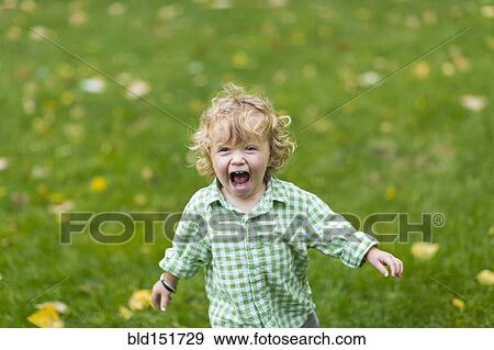 Stock Photo - Caucasian boy laughing in field. Fotosearch