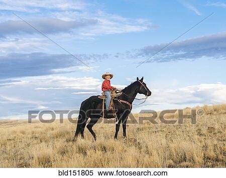 Stock Photography - Caucasian boy on horseback on grassy hill. Fotosearch