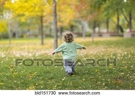 Stock Image - Caucasian boy running on grass lawn. Fotosearch
