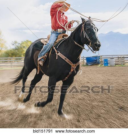 Stock Image - Caucasian boy using lasso on horse at rodeo. Fotosearch