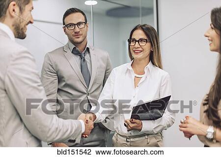 Stock Image - Caucasian business people shaking hands in office. Fotosearch
