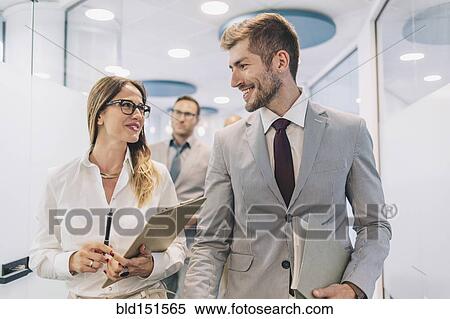 Stock Photography - Caucasian business people talking in office corridor. Fotosearch