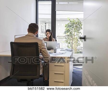 Stock Image - Caucasian business people working at desks in office. Fotosearch