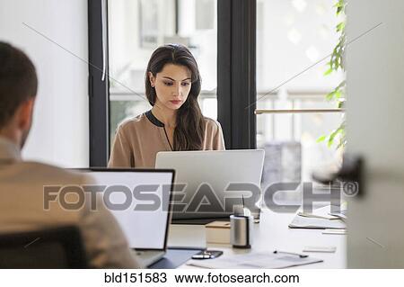 Stock Image - Caucasian business people working at desks in office. Fotosearch
