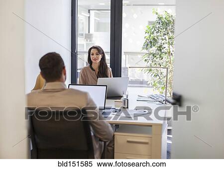 Stock Photography - Caucasian business people working at desks in office. Fotosearch