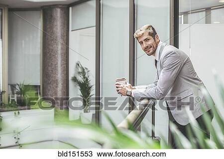 Stock Image - Caucasian businessman drinking coffee on office balcony. Fotosearch