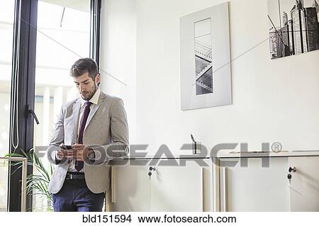 Caucasian businessman using cell phone in office View Large Photo Image Picture - Caucasian businessman using cell phone in office. Fotosearch