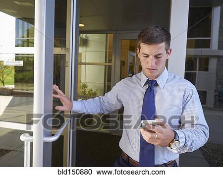 Stock Image - Caucasian businessman using cell phone outside office building. Fotosearch