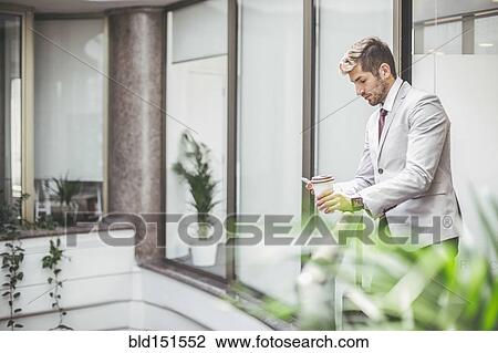 Stock Image - Caucasian businessman using cell phone on office balcony. Fotosearch