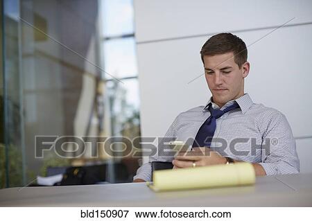 Stock Photo - Caucasian businessman using cell phone in office. Fotosearch