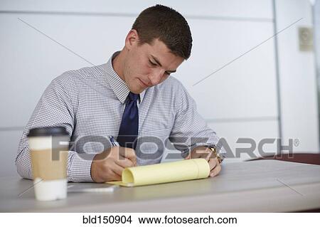 Caucasian businessman writing on notepad in office View Large Photo Image Picture - Caucasian businessman writing on notepad in office. Fotosearch