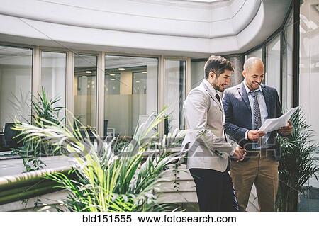 Caucasian businessmen reading paperwork on office balcony View Large Photo Image Stock Photography - Caucasian businessmen reading paperwork on office balcony. Fotosearch