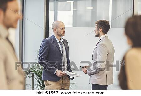 Stock Photo - Caucasian businessmen talking in office. Fotosearch
