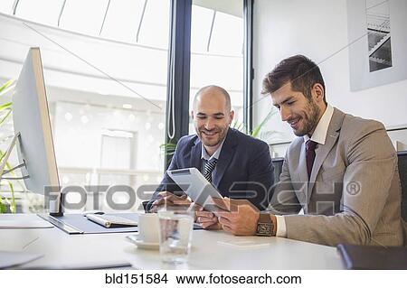 Picture - Caucasian businessmen using digital tablet in office. Fotosearch