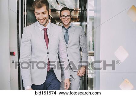 Picture - Caucasian businessmen walking out of elevator. Fotosearch