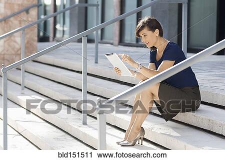 Stock Image - Caucasian businesswoman using digital tablet on staircase. Fotosearch