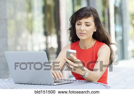 Caucasian businesswoman using laptop and cell phone outdoors View Large Photo Image Stock Image - Caucasian businesswoman using laptop and cell phone outdoors. Fotosearch