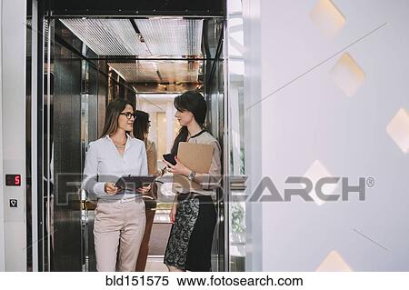 Caucasian businesswomen talking in elevator View Large Photo Image Stock Photography - Caucasian businesswomen talking in elevator. Fotosearch