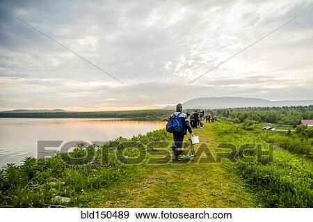 Stock Photo - Caucasian campers walking near rural lake. Fotosearch