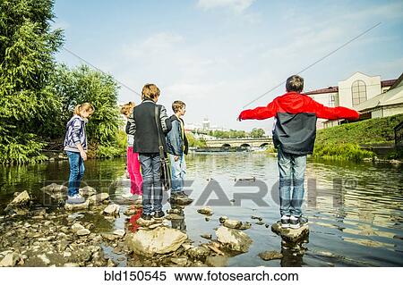 Stock Photography - Caucasian children playing on rocks in river. Fotosearch