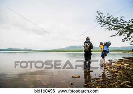 Stock Photograph - Caucasian couple backpacking near rural lake. Fotosearch