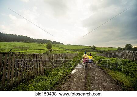 Stock Photo - Caucasian couple walking on rural dirt road. Fotosearch
