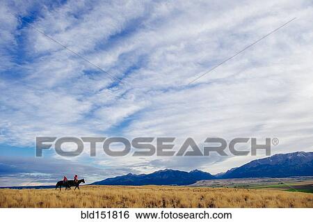 Stock Photograph - Caucasian herders riding horses in remote field. Fotosearch