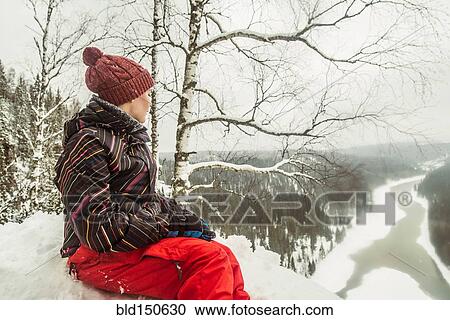 Stock Image - Caucasian hiker sitting on snowy hilltop. Fotosearch