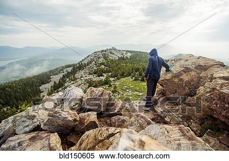 Stock Photography - Caucasian hiker standing on rocky hilltop. Fotosearch