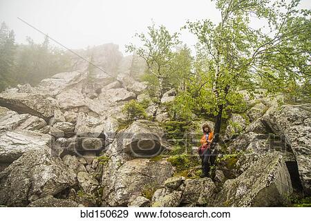 Caucasian hiker standing under tree on rocky hillside View Large Photo Image Stock Photo - Caucasian hiker standing under tree on rocky hillside. Fotosearch