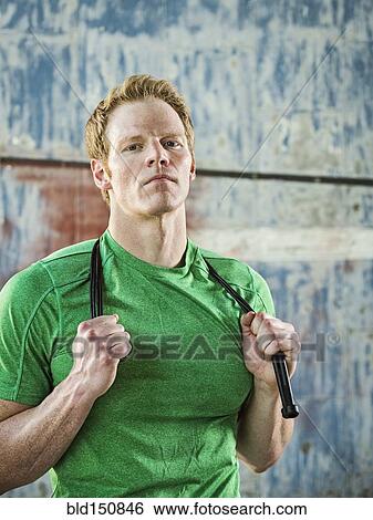 Stock Photograph - Caucasian man holding jump rope in warehouse. Fotosearch