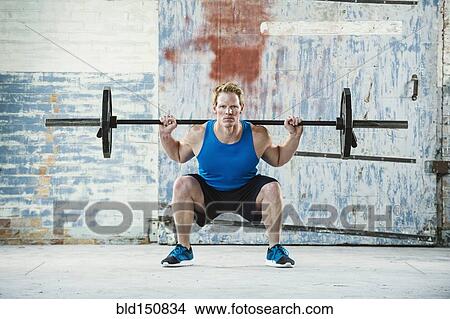Caucasian man lifting weights in warehouse View Large Photo Image Picture - Caucasian man lifting weights in warehouse. Fotosearch