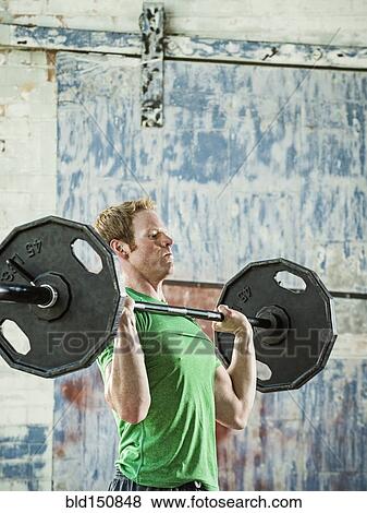 Caucasian man lifting weights in warehouse View Large Photo Image Stock Photo - Caucasian man lifting weights in warehouse. Fotosearch