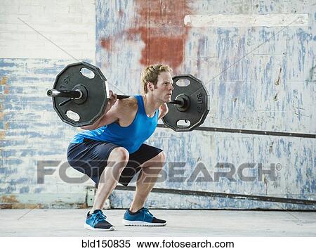 Caucasian man lifting weights in warehouse View Large Photo Image Stock Photography - Caucasian man lifting weights in warehouse. Fotosearch