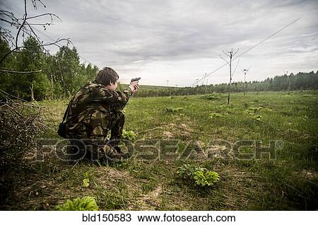 Caucasian man practicing shooting in rural field View Large Photo Image Stock Image - Caucasian man practicing shooting in rural field. Fotosearch