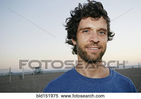 Stock Photography - Caucasian man smiling on beach. Fotosearch