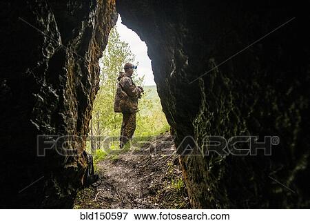 Caucasian man standing outside rock formation cave View Large Photo Image Stock Photo - Caucasian man standing outside rock formation cave. Fotosearch
