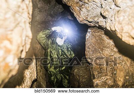 Caucasian man taking photograph in rock formation cave View Large Photo Image Stock Photo - Caucasian man taking photograph in rock formation cave. Fotosearch