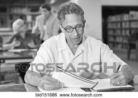 Caucasian man writing on notepad in library View Large Photo Image Stock Photograph - Caucasian man writing on notepad in library. Fotosearch