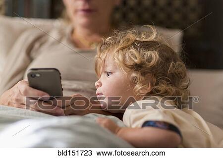 Stock Image - Caucasian mother and son playing with cell phone. Fotosearch