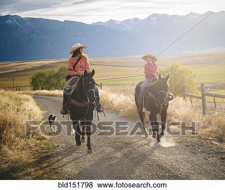 Stock Photo - Caucasian mother and son riding horses on ranch. Fotosearch