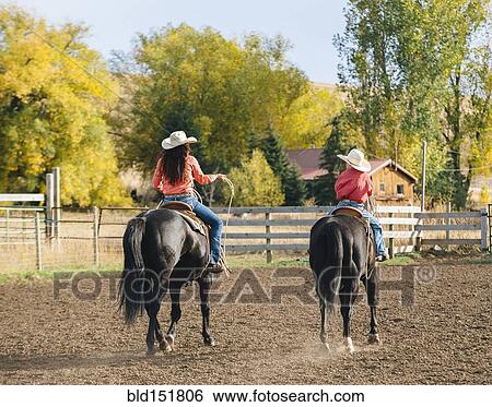 Stock Photograph - Caucasian mother and son riding horses on ranch. Fotosearch