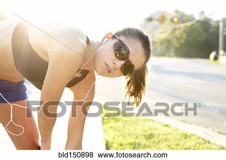 Stock Photo - Caucasian runner stretching on sidewalk. Fotosearch